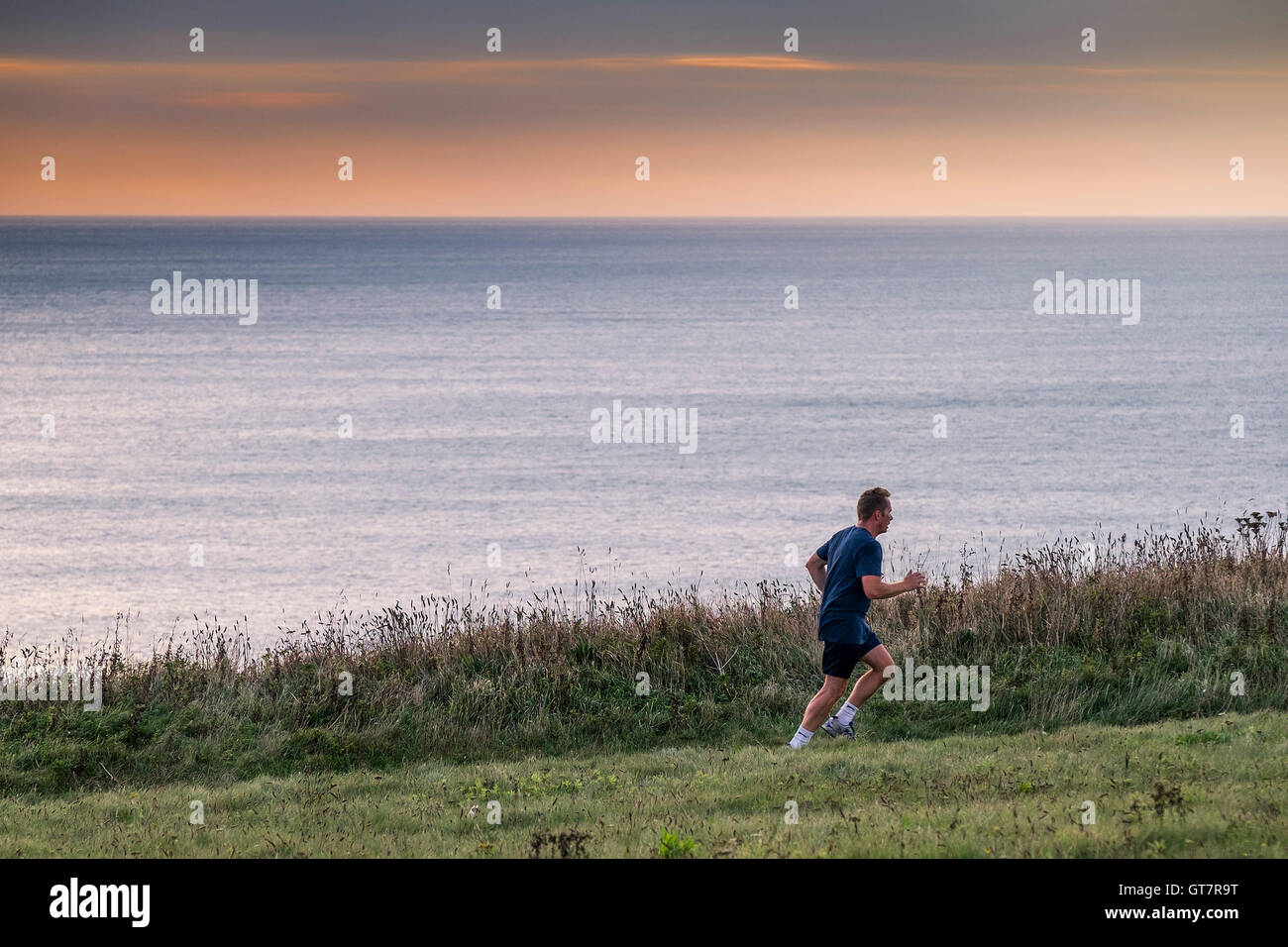 Ein Mann läuft entlang der South West Coastal Path zwischen Newquay und Watergate Bay in Cornwall. Stockfoto