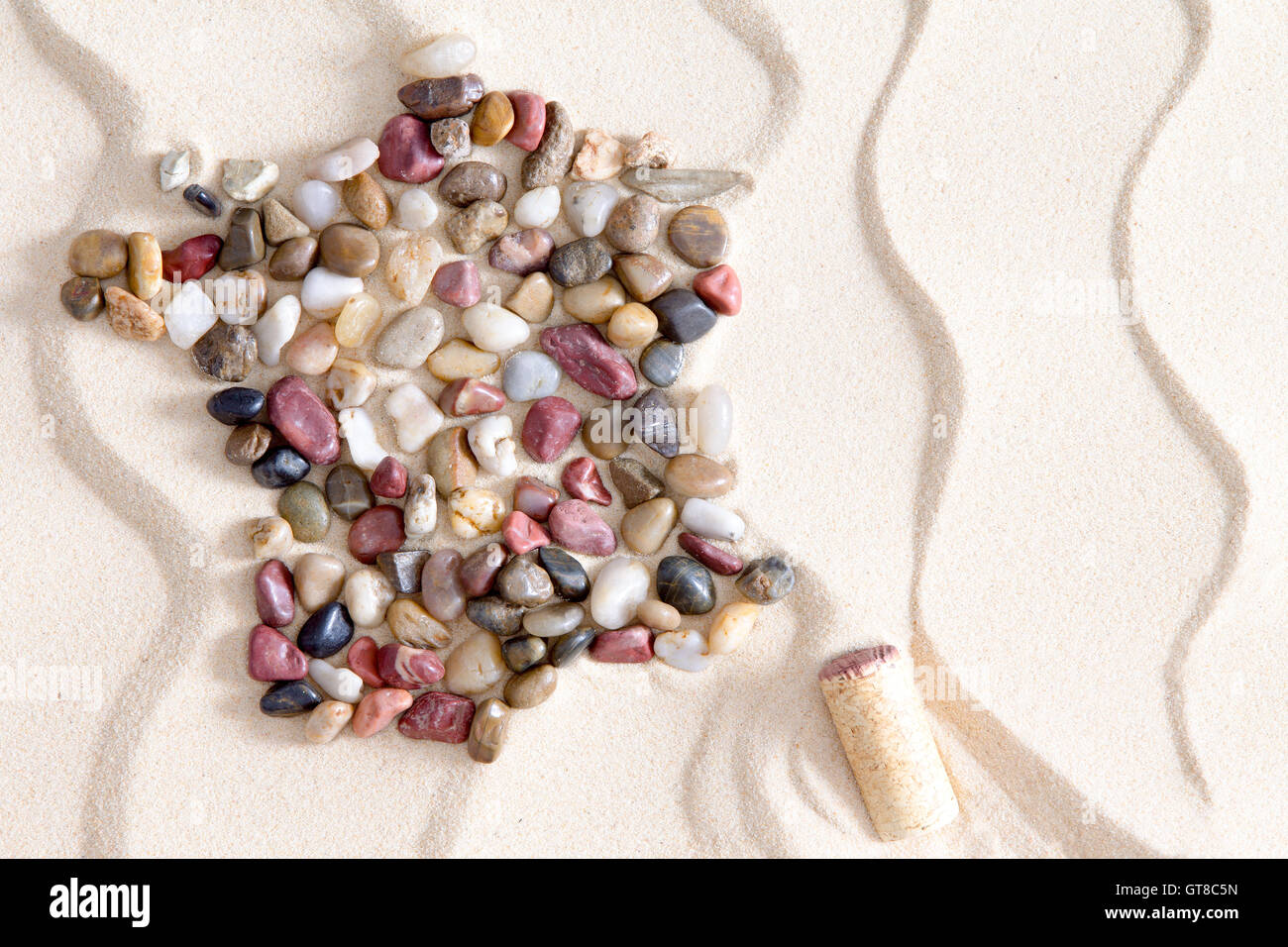 Künstlerische Karte von Frankreich aus bunten Fersenone Kieseln arrangiert auf dekorativen weißen Sand mit einem Muster von Wellenlinien mit Corsi Stockfoto