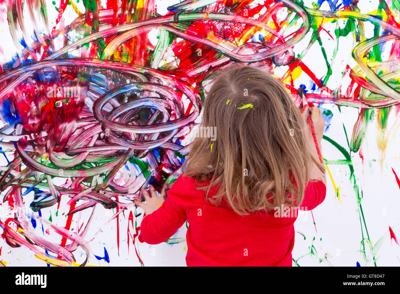 Nahaufnahme junge blonde Kind Malerei abstrakte Design verwenden verschiedene Farben auf weiße Wand während ihrer Malerei-Zeit. Stockfoto