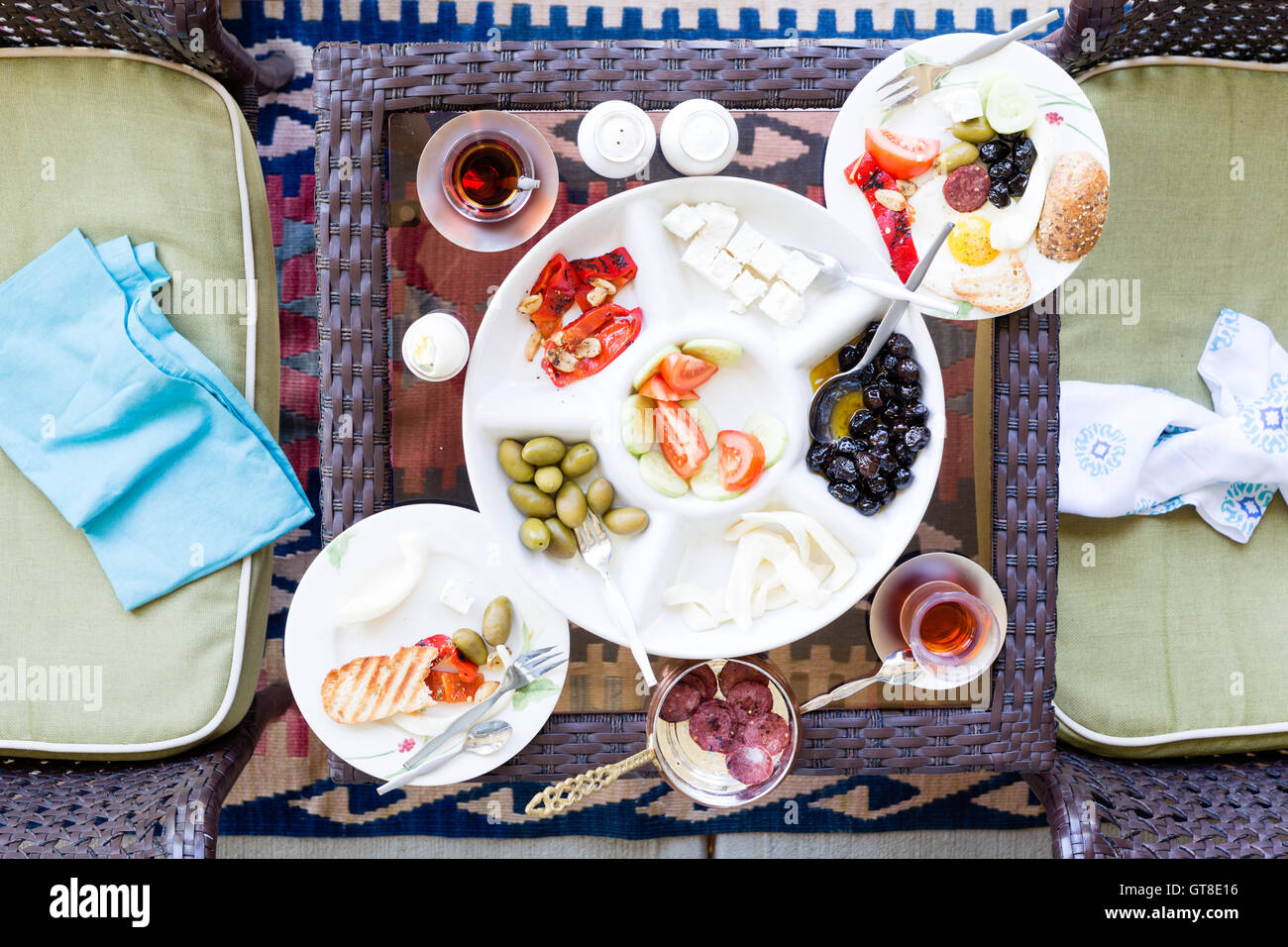 Unvollendete türkisches Frühstück auf einer Terrassentisch mit einer Portion Spiegeleier mit einer Auswahl an frischen Tomaten, Oliven, Käse und Stockfoto
