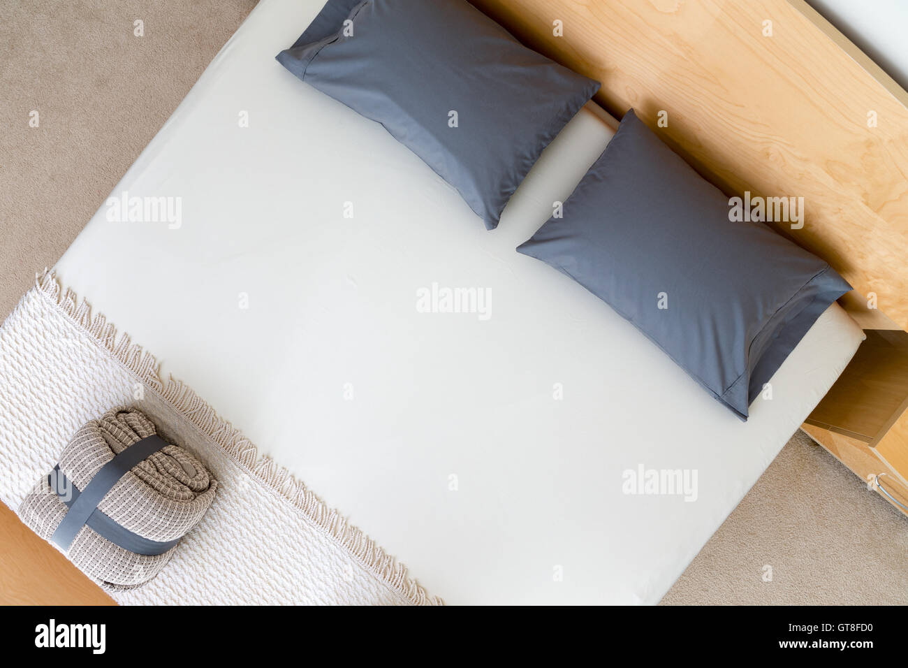 Draufsicht auf ein ordentlich King size-Bett in einem Hotel oder Haus mit schwarzen Kissen auf einem weißen Bettdecke mit einem gefalteten und geschnallt Stockfoto