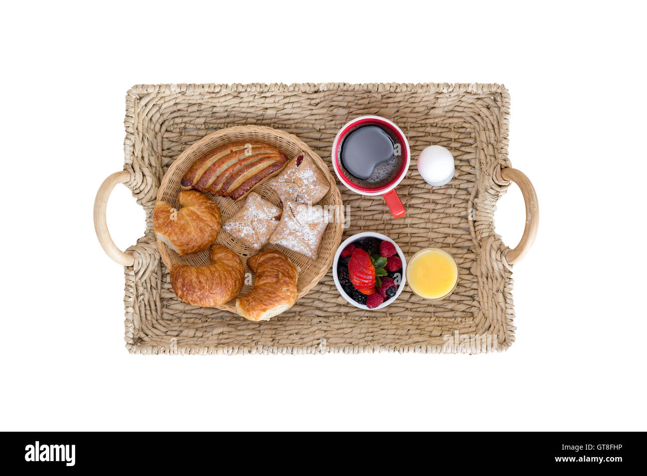 High Angle View of Wicker Frühstückstablett mit Sortiment an Broten und Beeren, Kaffee, Saft und hart gekochtes Ei auf weiß Stockfoto