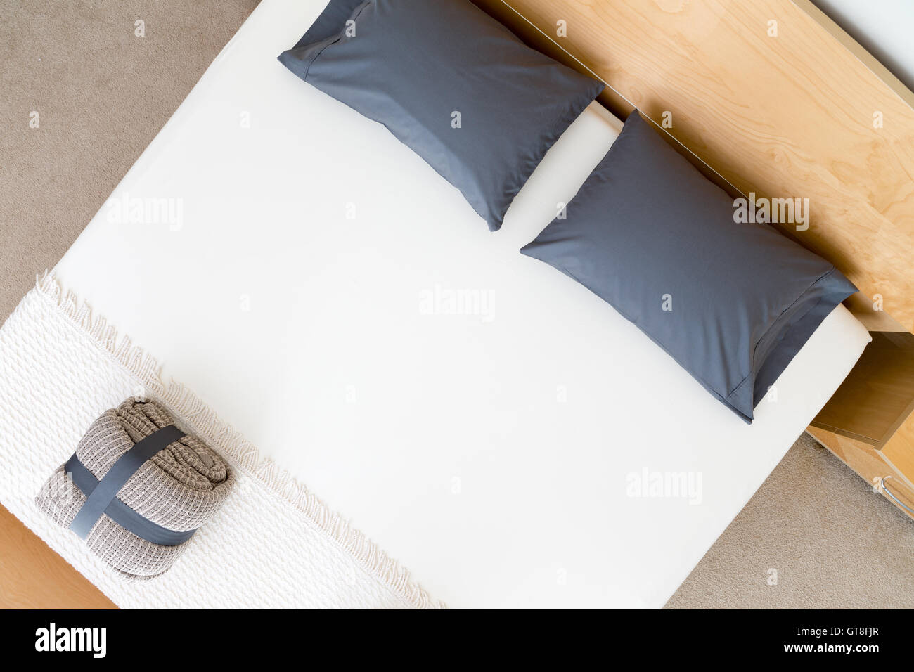 Draufsicht auf ein ordentlich King size-Bett in einem Hotel oder Haus mit schwarzen Kissen auf einem weißen Bettdecke mit einem gefalteten und geschnallt r Stockfoto