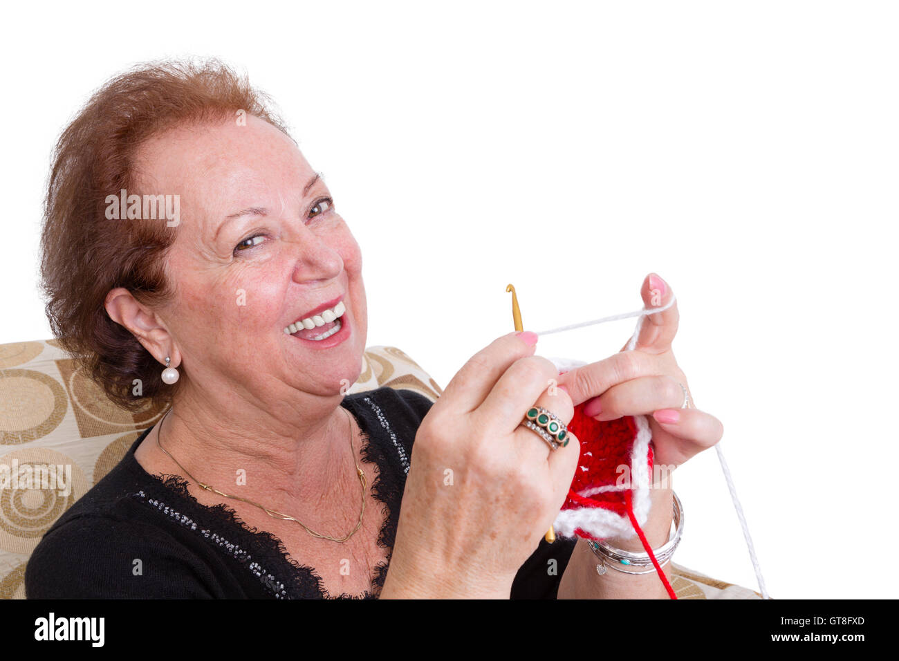 Elegante senior Lady sitzend stricken eine bunte rote Element schließen wie sie genießt ihren Ruhestand auf Kopf und Schultern über lachen Stockfoto