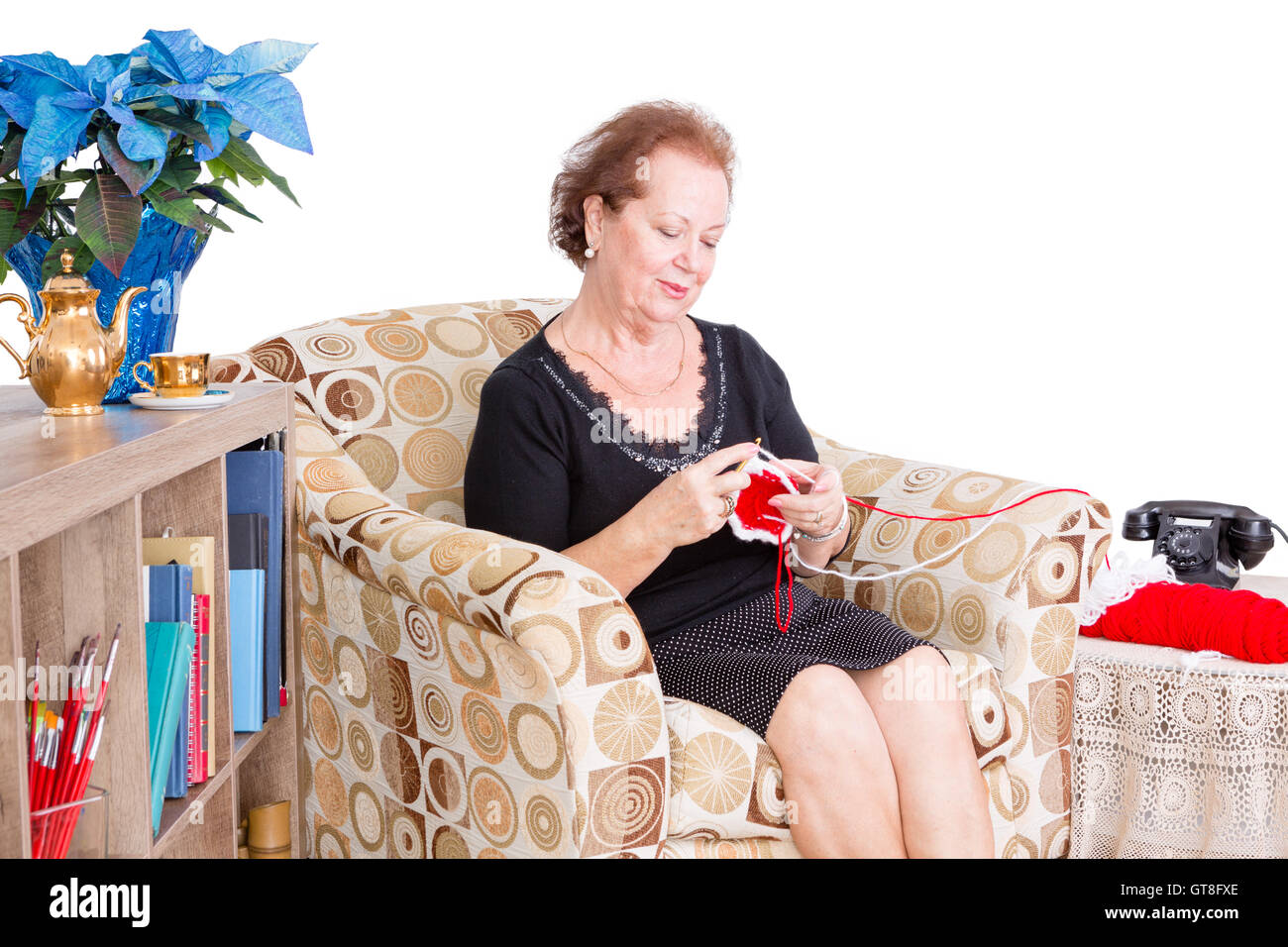 Oma zu Hause sitzen in einem bequemen Sessel im Wohnzimmer tun ihr stricken mit einem Blick der zufriedenen Genuss Stockfoto