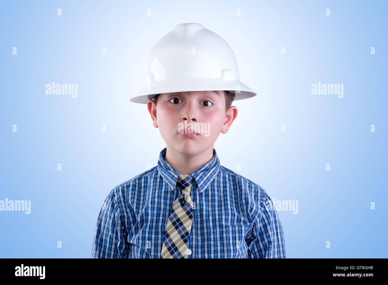 Aufstrebende junge Tween jungen träumen davon, ein Ingenieur in Bauarbeiterhelm und Krawatte mit einem skurrilen Ausdruck - ich werde sein Stockfoto