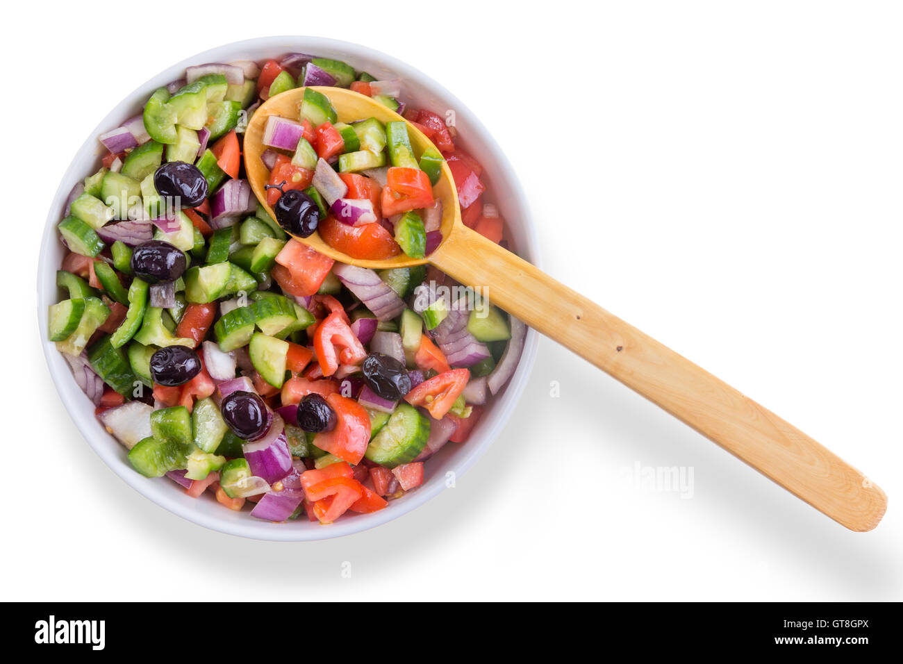 Frische bunte türkische Hirten Salat mit Oliven, serviert in einer Runde Schüssel mit einem hölzernen Löffel als gesunde Ergänzung Stockfoto
