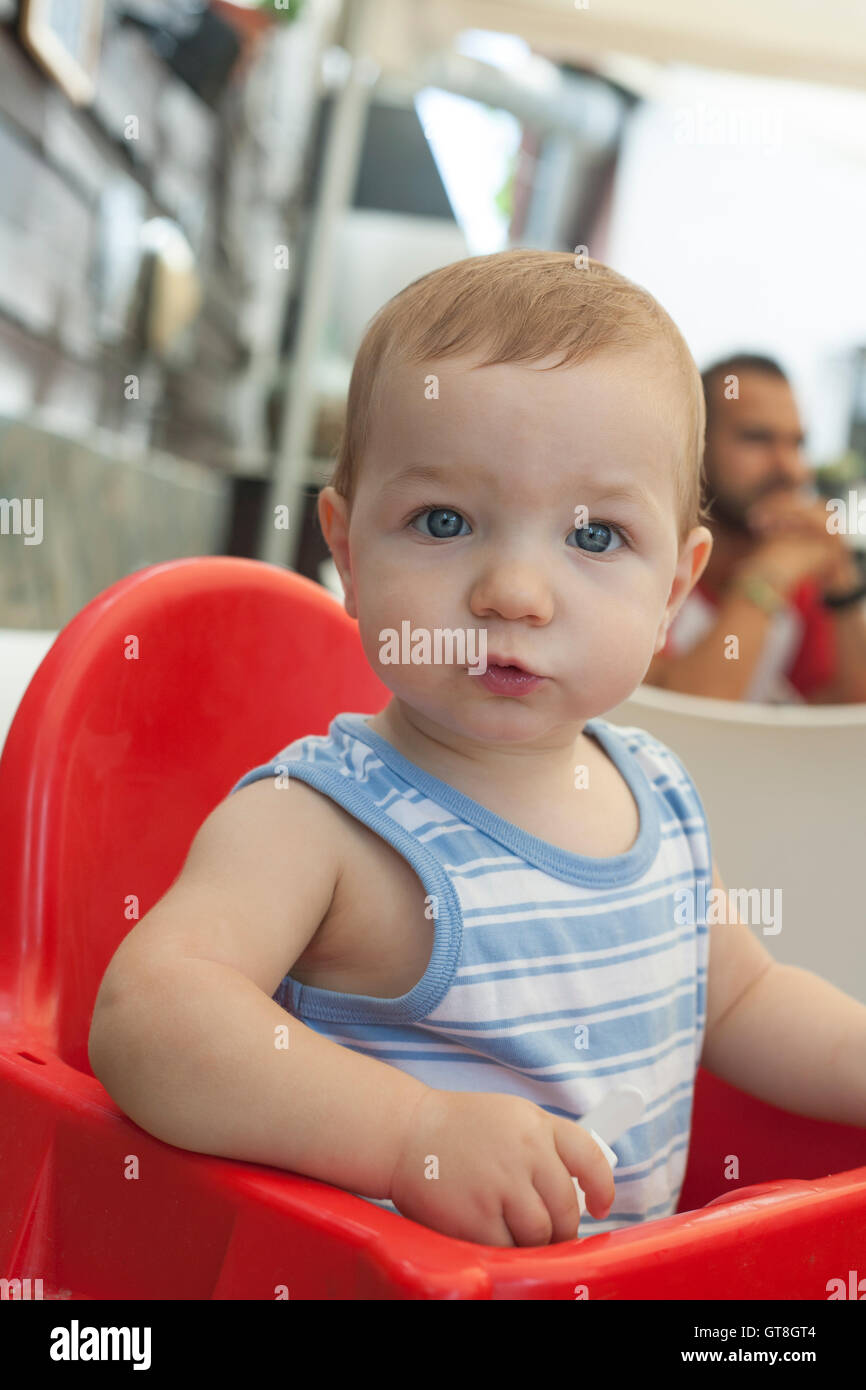 Baby Junge sitzen im Hochstuhl im Restaurant mit Terrasse. Sommer-Saison Stockfoto