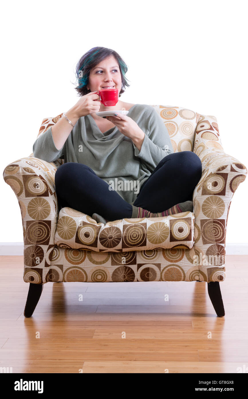 Erfreut Frau mittleren Alters zu Hause sitzen bequem in Sofa Sessel ihren Morgenkaffee genießen Stockfoto