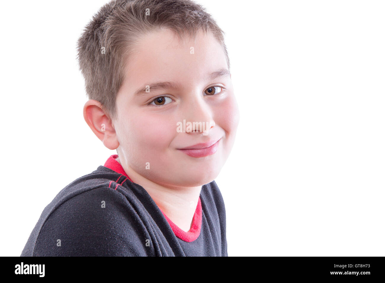 Kopf und Schultern Close Up Portrait Tween jungen schwarzen und roten T-Shirt und lächelnd über die Schulter in die Kamera im Stu Stockfoto