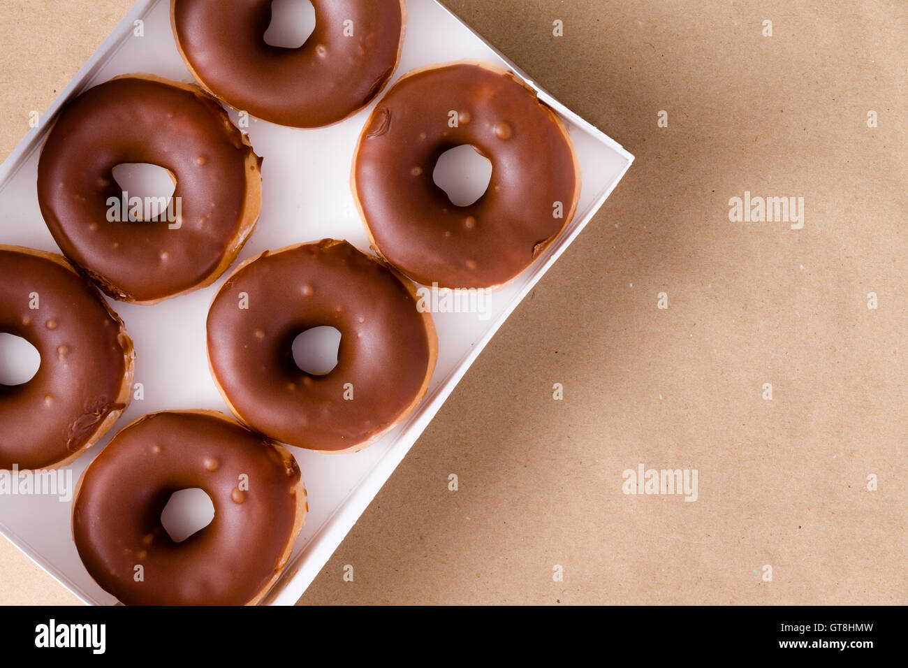 First-Person Perspektive von oben nach unten Ansicht von sechs Schokolade und Creme Donuts in offener Kasten über braunen Tisch mit Textfreiraum Stockfoto