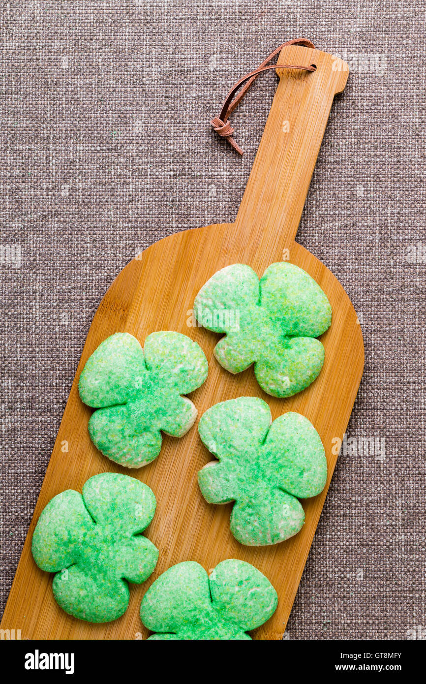 Hausgemachte grüne Kleeblatt Cookies für St. Patricks Day auf einer Flasche geformt Holzbrett symbolisch für das traditionelle Getränk - Drow Stockfoto