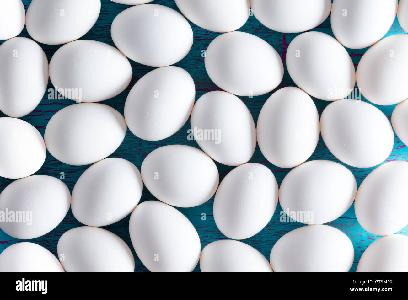 Hintergrundmuster von mehreren kleinen weißen Zucker überzogen Ostern Eiern auf einem blauen Picknick-Tisch als eine Schicht von oben betrachtet Stockfoto