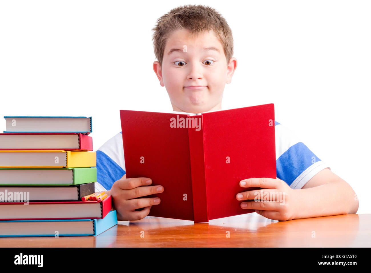 Young überrascht Grundschule Schüler verblüfft an Fakten, die er in seinem Schulbuch betrachten sie mit einem Blick von Amaz liest Stockfoto