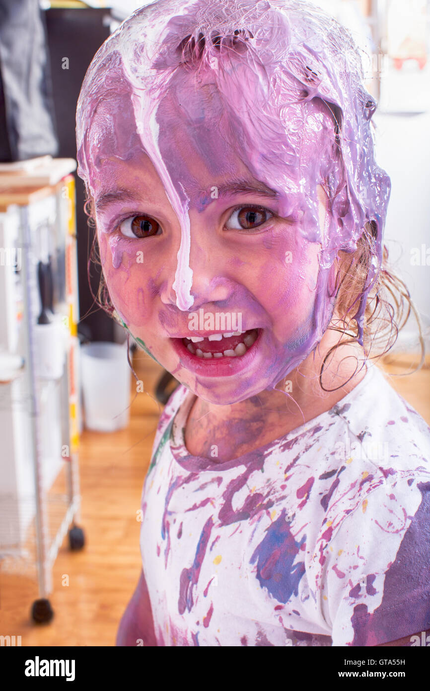 Glücklich einzelne kleine zukünftige Künstlerin bedeckt in verschiedenen Farben der Farbe im indoor Art studio Stockfoto