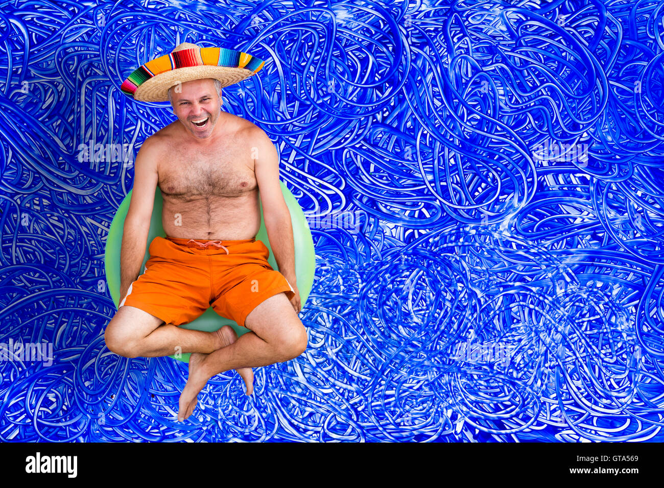 Glückliche Mann mittleren Alters in den Sommerferien sitzen in seine Badehose und Sombrero auf einer bunten grüne Röhre lachen sich an der Kamera Stockfoto
