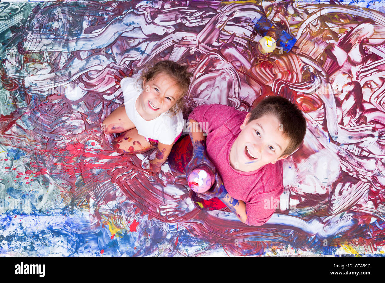 Glückliches Mädchen und junge blickte, während in Farbe von Wandgemälde teilweise bedeckt sind sie mit ihren Händen machen. Stockfoto