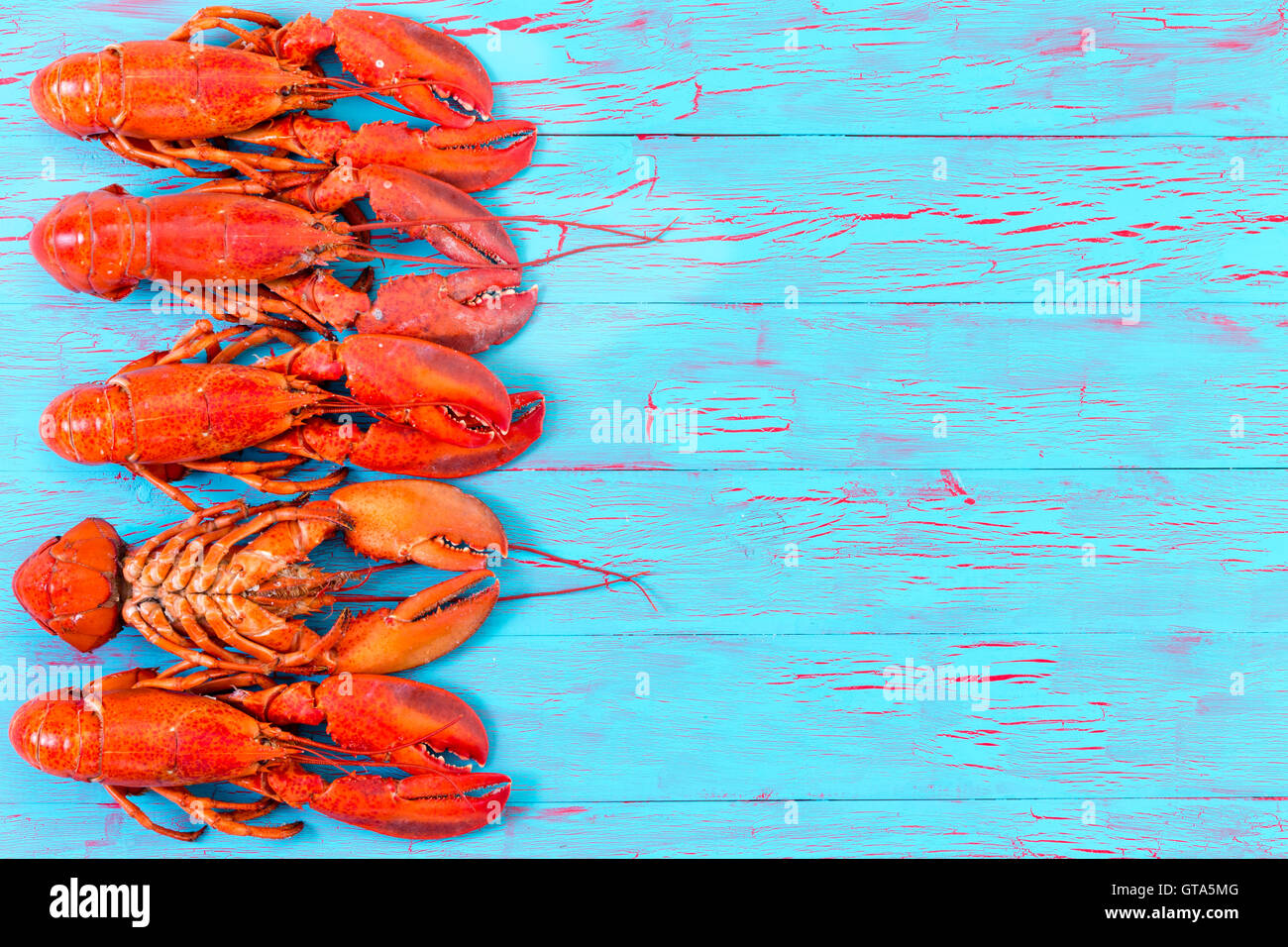 Auf eine exotische Knistern Glasur blau Holz Picknick-Tisch für einen bunten Sommer oder Essen Hintergrund mit einem bunten roten Hummer Grenze Stockfoto