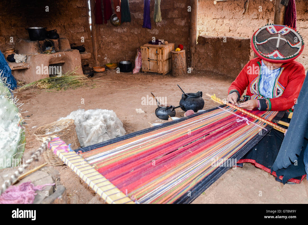 Einheimische Cusquena Frau in bunten Trachten gekleidet arbeitet auf einem Webstuhl vor ihrem Haus Stockfoto