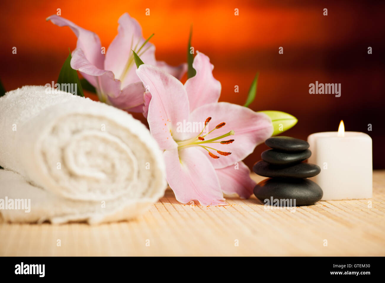 Spa-Konzept der Lilie Blume, Handtücher, Meersalz, Kerze und Crystal Rock rosa Quarz auf warmen hölzernen Hintergrund. Stockfoto