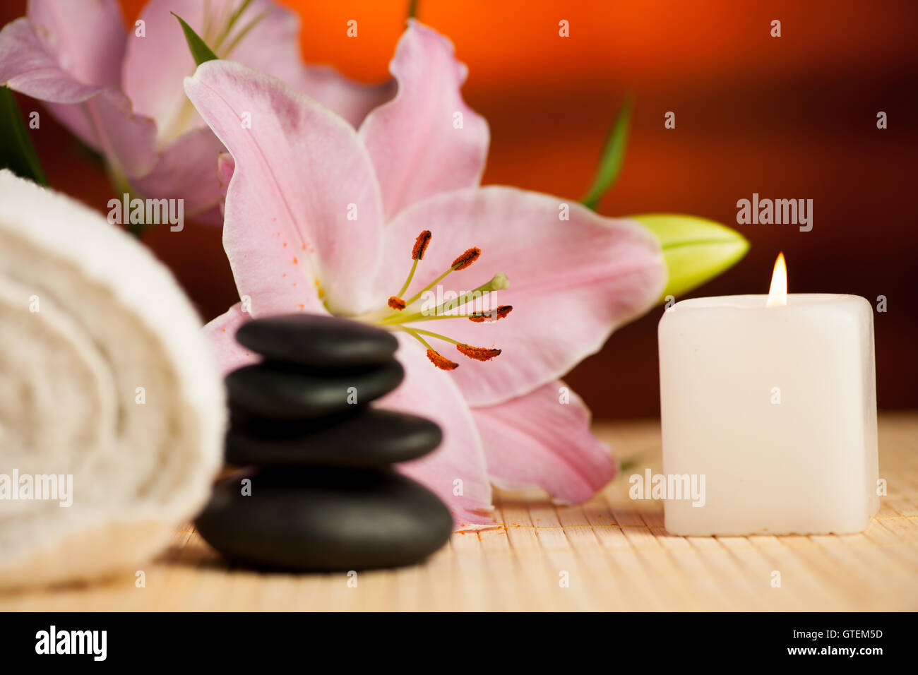 Spa-Konzept der Lilie Blume, Handtücher, Meersalz, Kerze und Crystal Rock rosa Quarz auf warmen hölzernen Hintergrund. Stockfoto