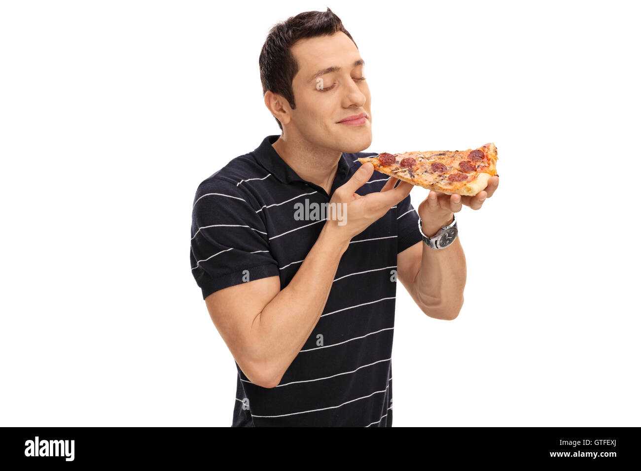 Junger Mann riecht ein Stück Pizza isoliert auf weißem Hintergrund Stockfoto