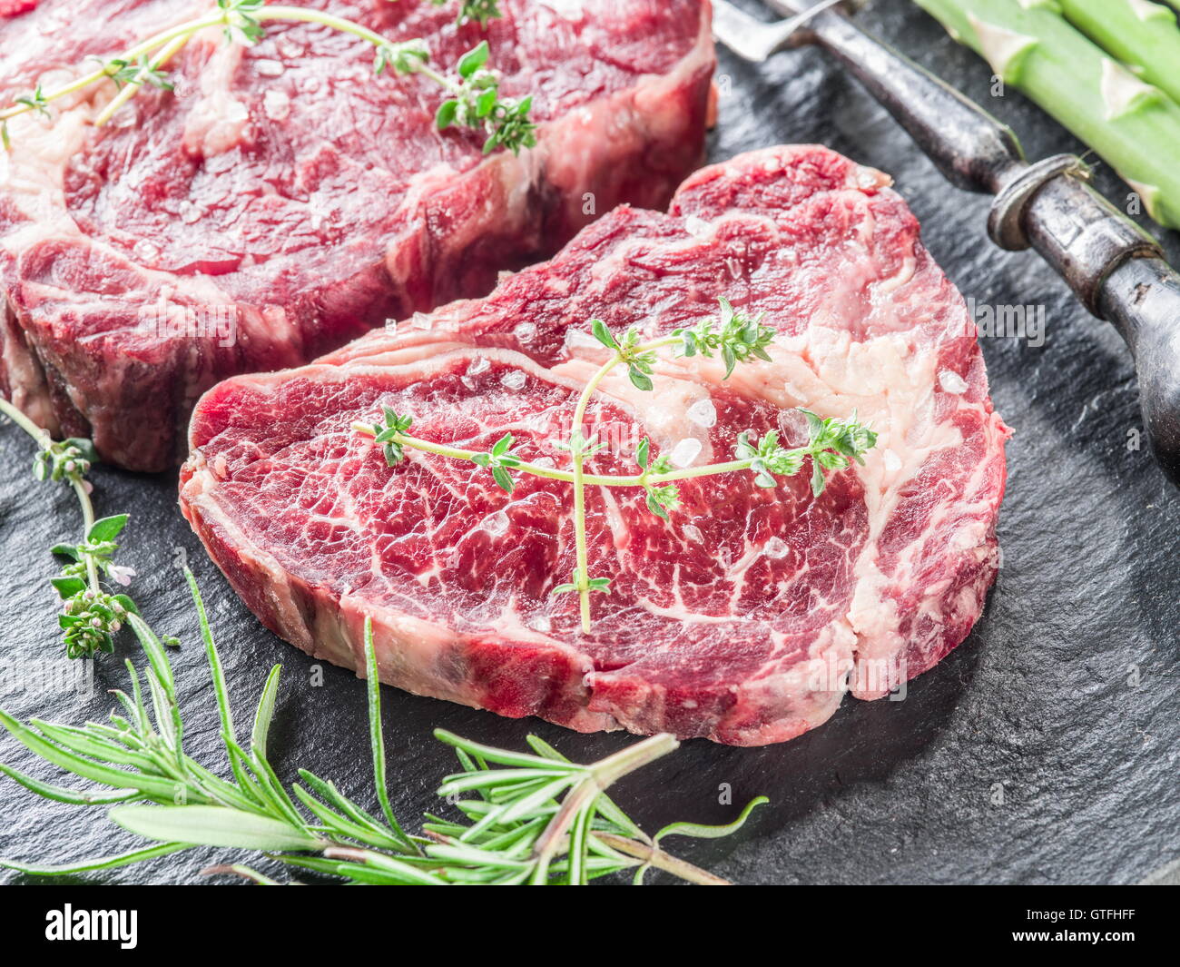 Rib-Eye Steak mit Gewürzen auf dem schwarzen Hintergrund. Stockfoto
