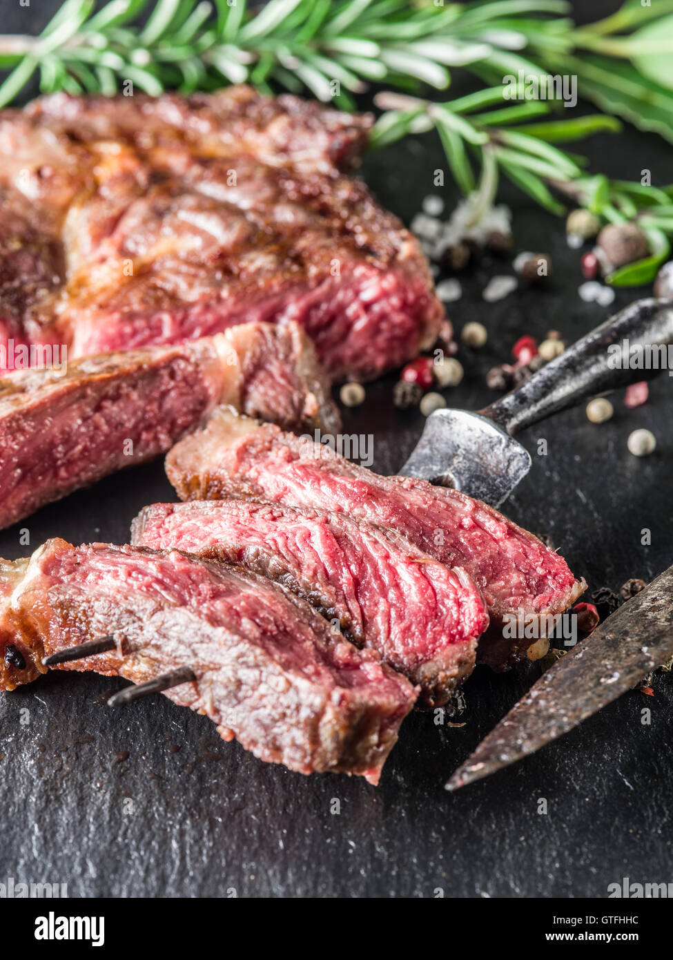 Mittlere Ribeye-Steak mit Gewürzen auf dem Graphit-Tablett. Stockfoto