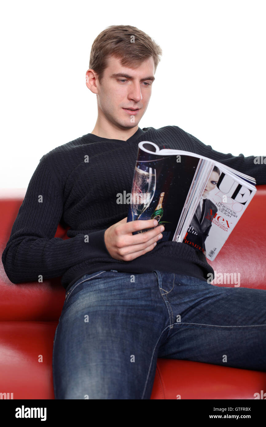 junger Mann mit Magazin auf Sofa sitzen Stockfoto