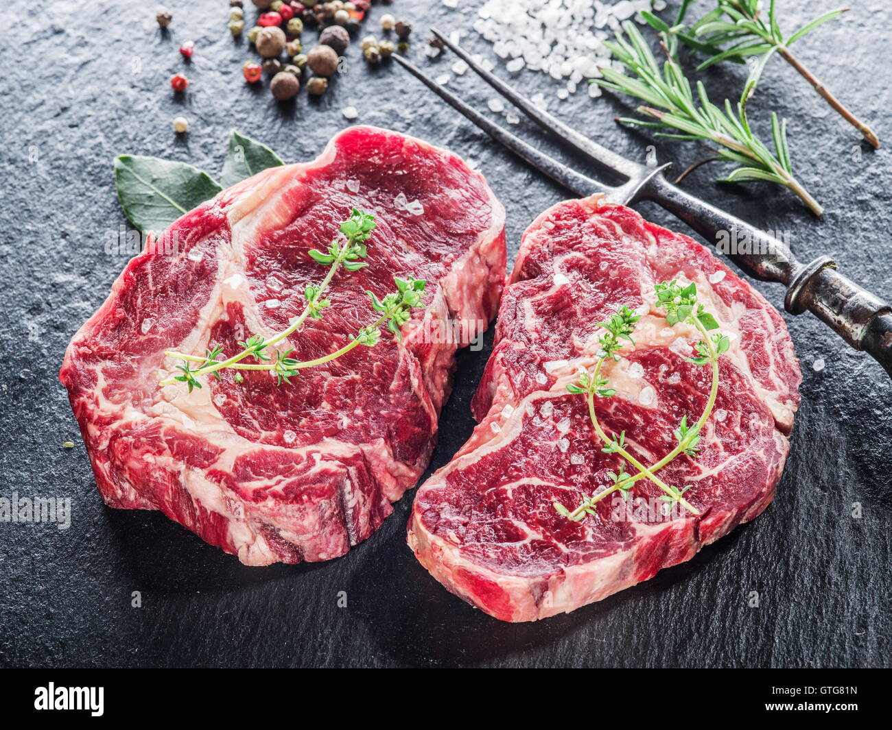Rib-Eye Steak mit Gewürzen auf dem schwarzen Hintergrund. Stockfoto