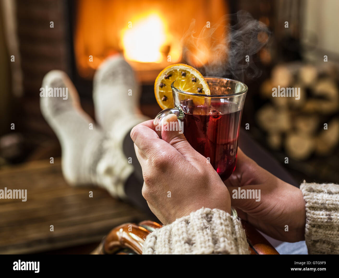 Heißer Glühwein und Buch in Händen der Frau. Entspannen vor Feuer in den kalten Wintertag. Stockfoto