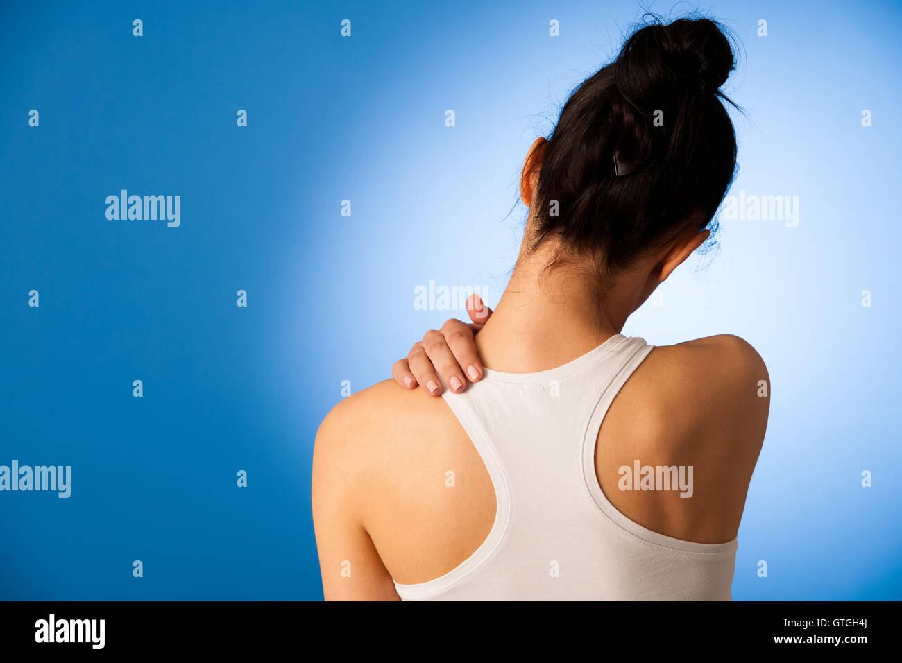 Frau mit Schmerzen im Nacken auf blauem Hintergrund Stockfoto