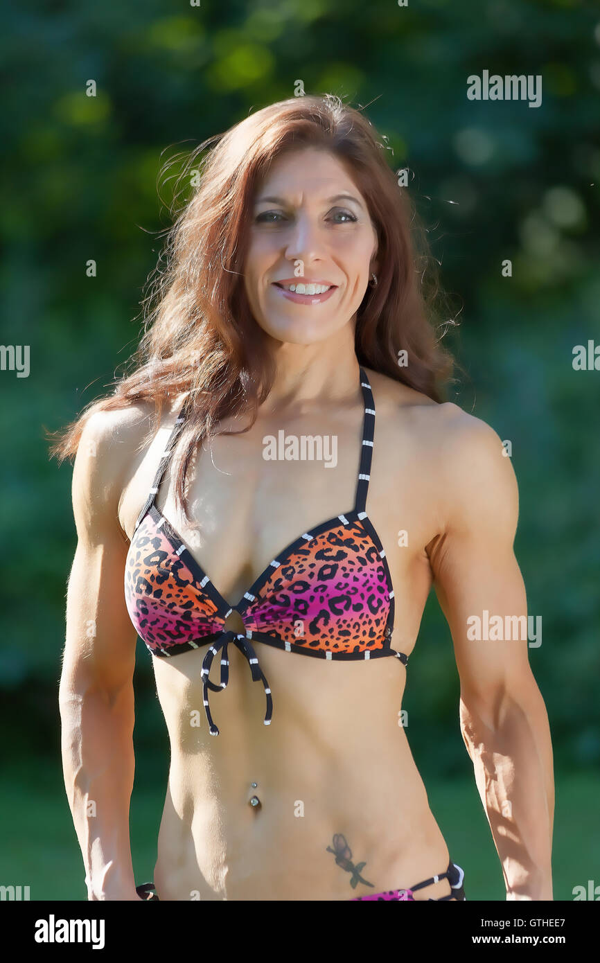 Weiblich Alter 42 posiert im Park im Freien als Bodybuilder und Fitness-Experte in ihrem bikini Stockfoto