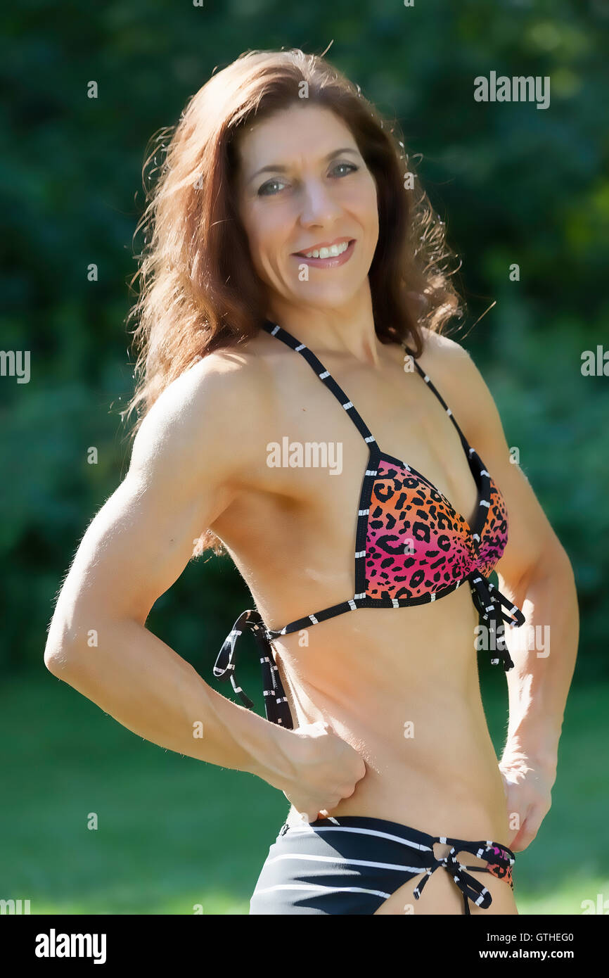 Weiblich Alter 42 posiert im Park im Freien als Bodybuilder und Fitness-Experte in ihrem bikini Stockfoto