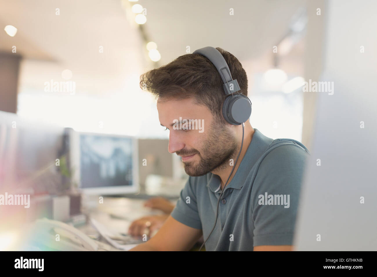 Kreative Geschäftsmann mit Kopfhörern, die im Büro arbeiten Stockfoto