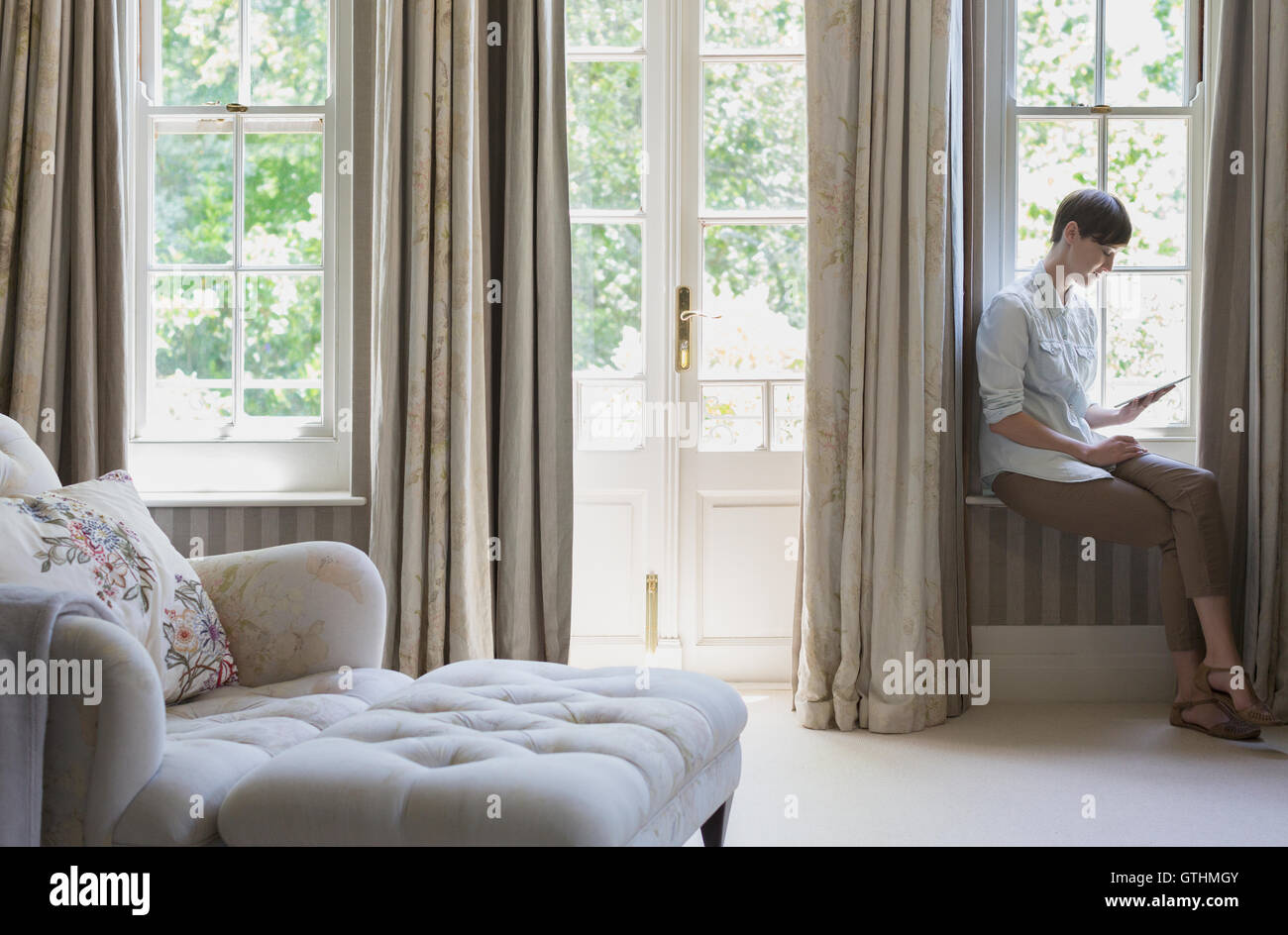 Frau mit digital-Tablette am Fenster im Schlafzimmer Stockfoto