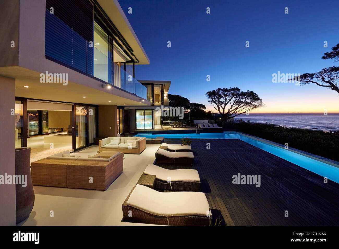 Moderne Luxus nach Hause Schaufenster Terrasse mit beleuchteten Pool in der Dämmerung Stockfoto