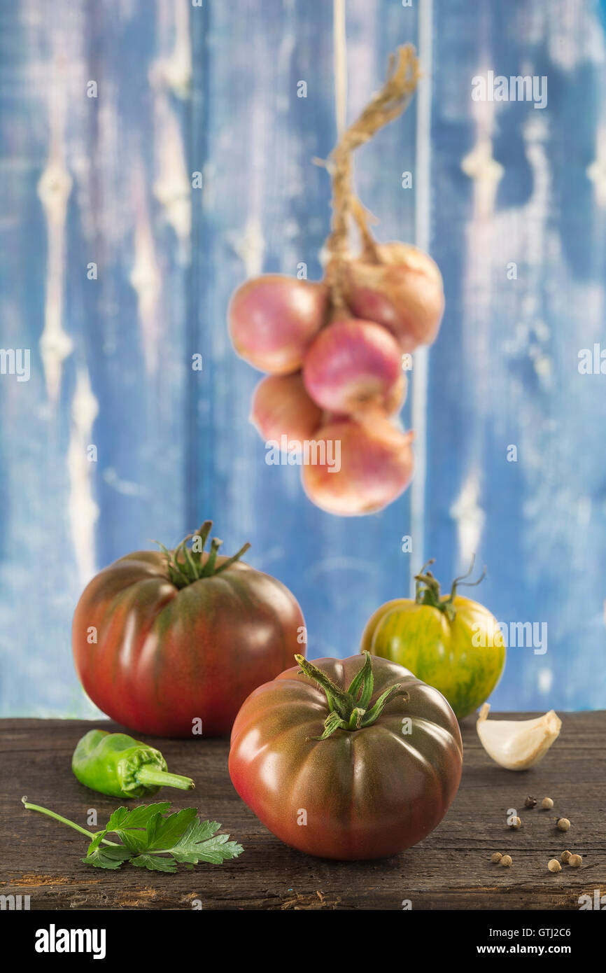 Frisches Gemüse auf alten blauen hölzernen Hintergrund - Tomaten, Petersilie, Knoblauch, Pfeffer, Zwiebel, Basilikum Stockfoto