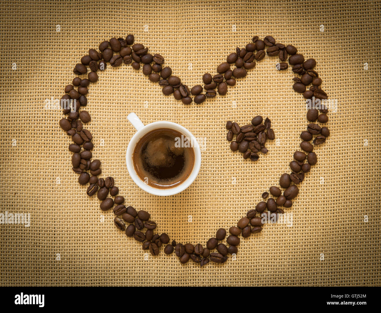 Kaffeebohnen in der Form von Herz-Symbol und eine Tasse schwarzen Espressokaffee. Konzept der ich liebe Kaffee. Stockfoto