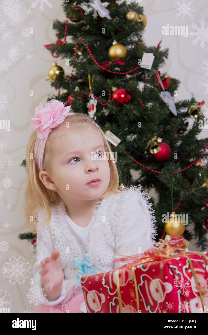 Mädchen unter Weihnachtsbaum mit Geschenken Stockfoto