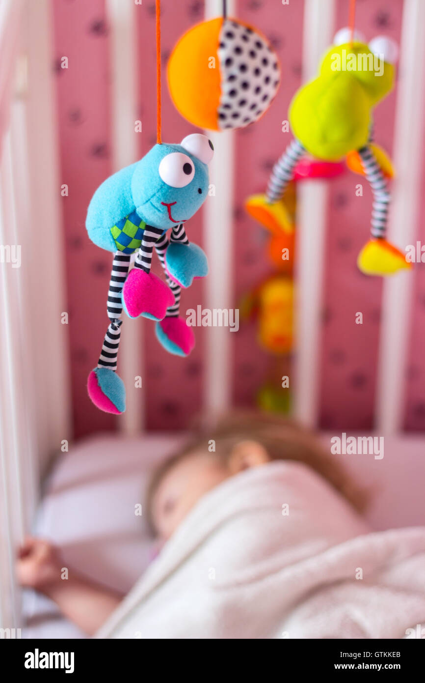 Baby-Bett mit mobile Spielzeug darüber; Baby schläft Stockfoto