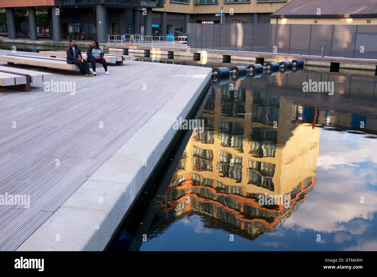 Ein nahe gelegenes Gebäude spiegelt sich im ruhigen Wasser des Paddington Basin, Floating Pocket Park, London, Großbritannien, wider Stockfoto