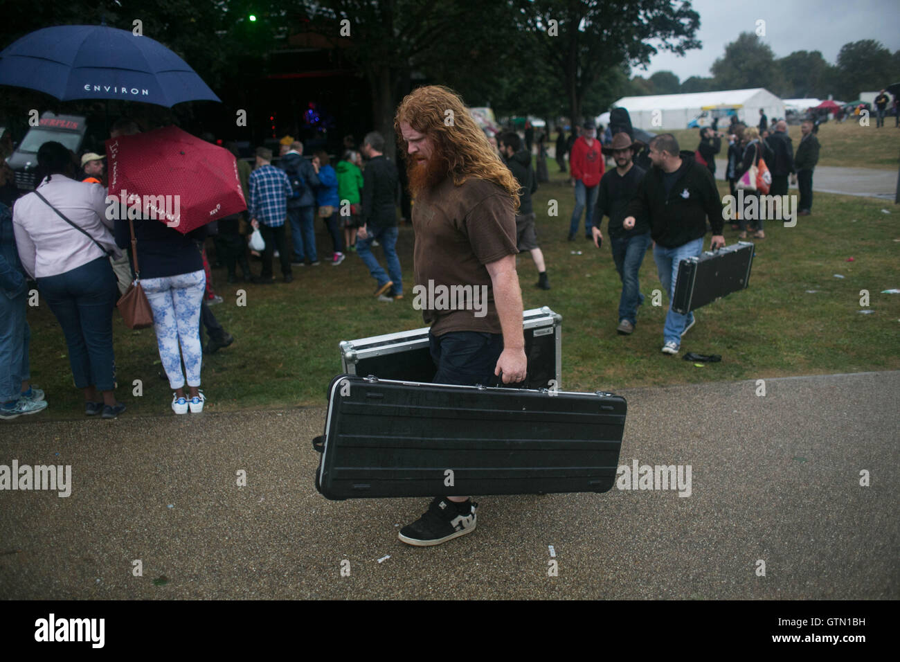 Ein Band-Mitglied der Alternative Parkplatz trägt seine Ausrüstung um ihre van im Regen nach ihren Auftritt, London, Großbritannien, 3. Sep Stockfoto