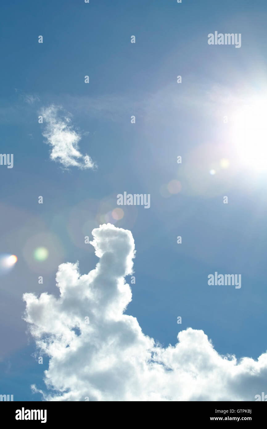 Dramatische Wolken vor blauem Himmel mit Lens flare von der Sonne. Stockfoto