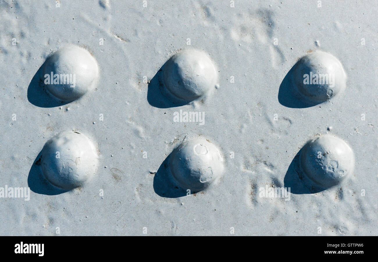 Sonnendurchflutetes grau lackiert Metalloberfläche mit zwei Reihen von sechs Nietköpfe Stockfoto