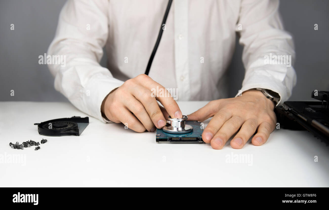 Mann repariert, um den Laptop blicken auf die Festplatte hält die Tabelle Schrauben und Schraubendreher zerlegen Stockfoto