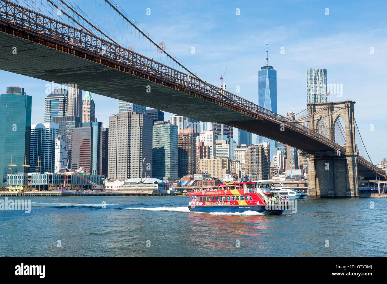 NEW YORK CITY - 27. August 2016: Eine bunte Fähre führt Touristen unter der Brooklyn Bridge auf eine Tour durch Manhattan. Stockfoto