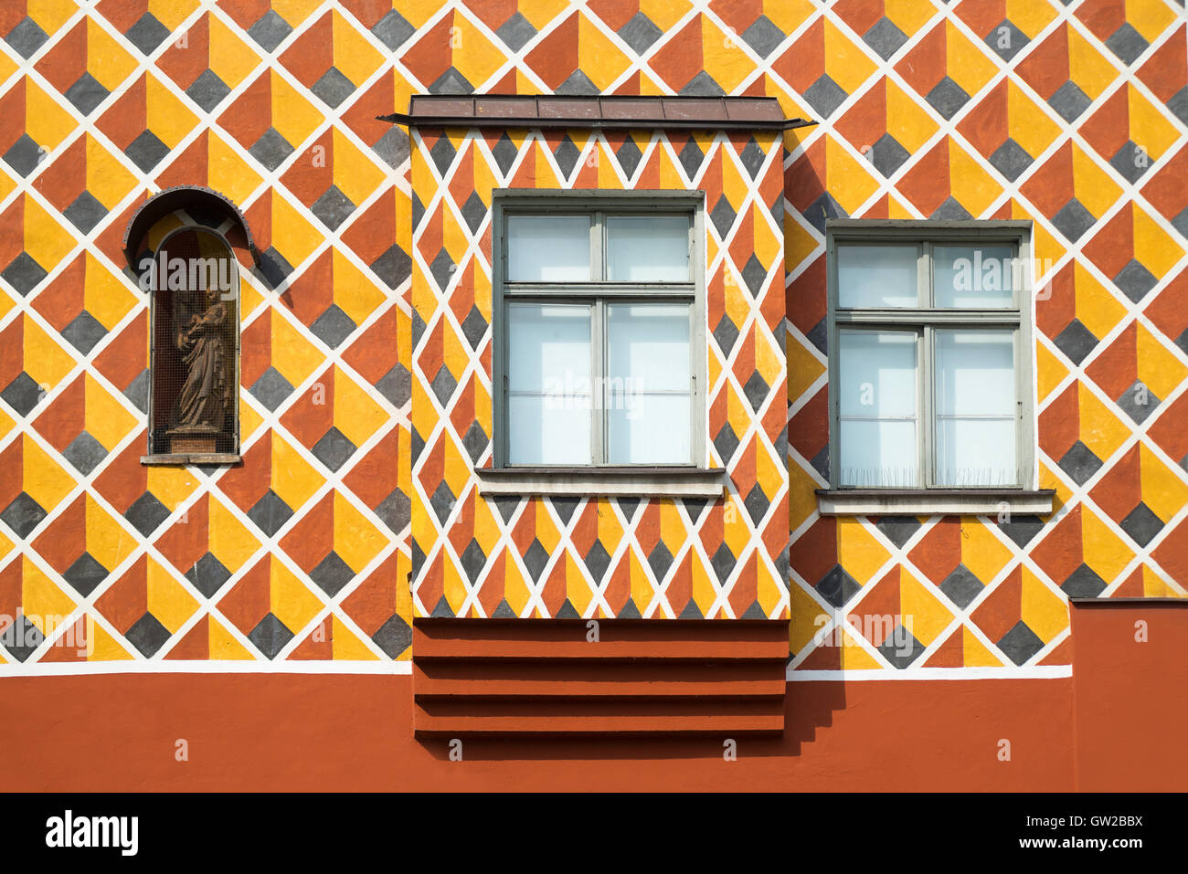 Windows und heilige Figur in einer bunt gemusterten Fassade eines mittelalterlichen Hauses in Wasserburg, Bayern, Deutschland Stockfoto
