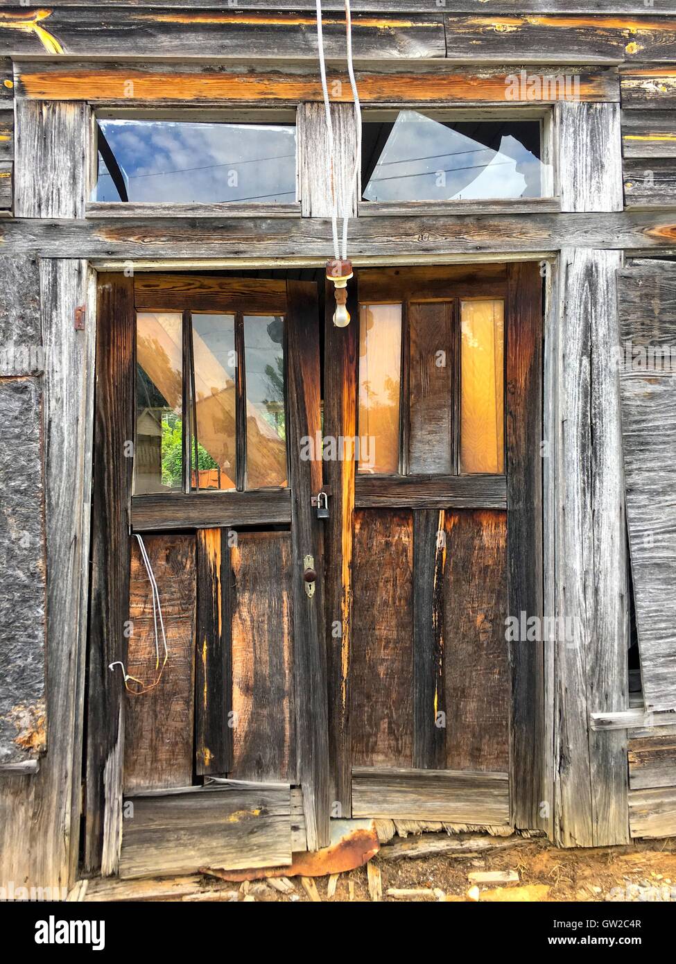Haustüren, eine alte verlassene Holzschuppen.  Ein Licht nach unten hängt und das Glas im Doppel ist gebrochen. Stockfoto