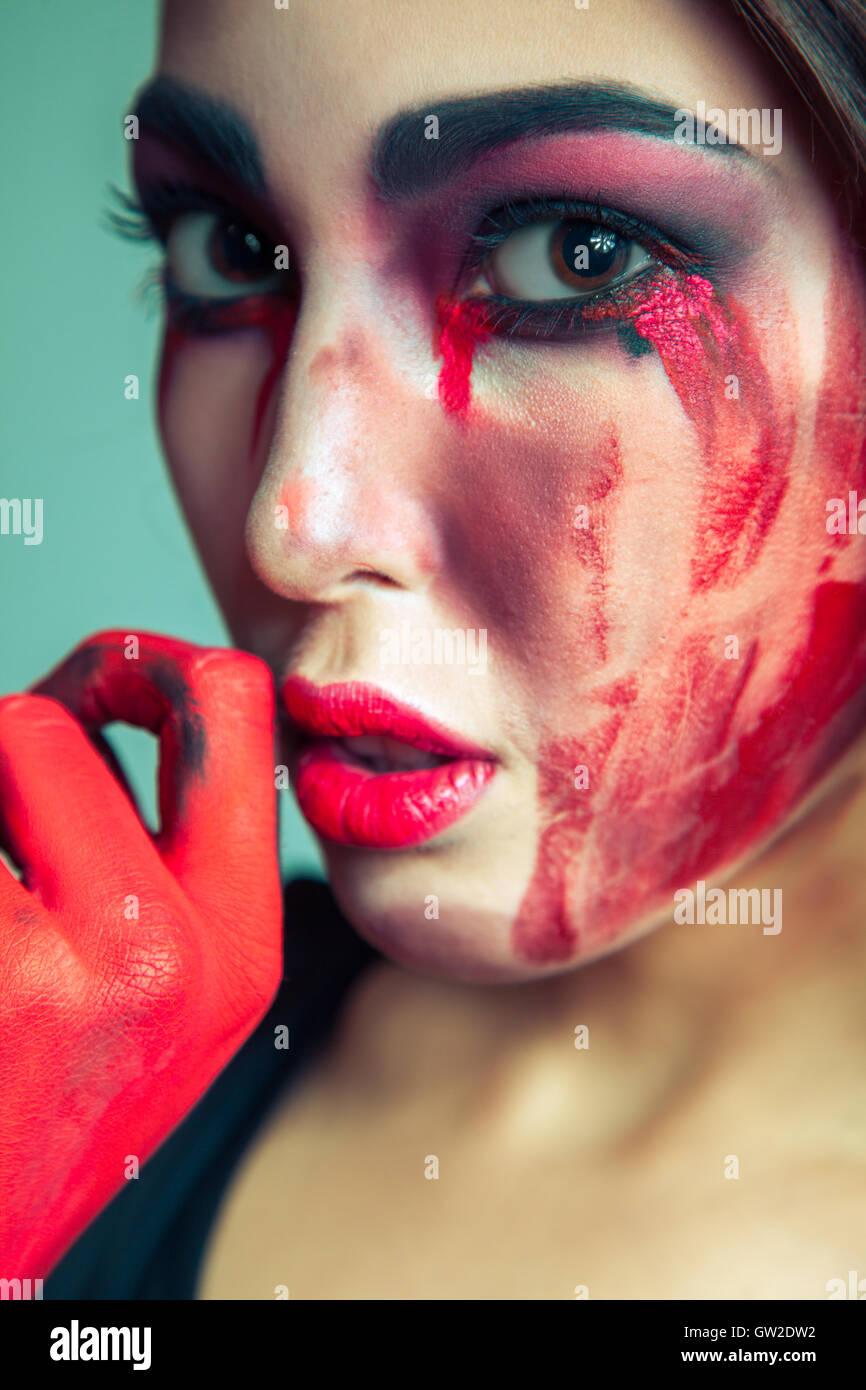 Porträt von Freak-Monster mit Chaos schmutzig gefärbt Make-up im Gesicht. weinende Frau mit roten blutige Tränen und Hand. Stockfoto